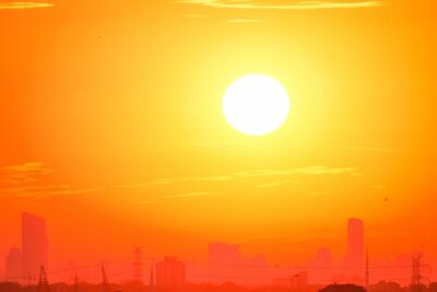A city skyline silhouetted against a vivid, orange sunset sky.
